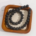 Macro shot of natural porous black lava beads showing matte texture in a wooden tray - 11mm Strand (Approx 39 Beads)