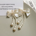 Orecchini a fiocco crema con nappe di perle bianche e dettagli in metallo dorato - Fiocco Bianco Perla