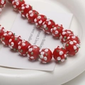 Close-up of handmade red glass flower beads with white petal patterns for DIY jewelry - 1 Piece/Pack (10x14mm) / Red