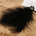 Detailed macro shot of vintage black feather earrings with beaded flower and crystal accents - Black