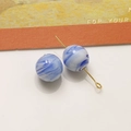 Dettaglio macro di una perla di vetro marmorizzato blu e bianco da 12mm su spilla d'oro - Blu scuro