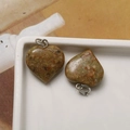 Close-up of heart-shaped natural stone pendants with silver loops on a ceramic plate - Greenish Yellow Heart
