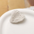 Close-up of handmade cream heart-shaped crochet applique on a white ceramic plate - White