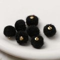 Makro-Detail von schwarzen Kunstpelz-Pompons mit goldenen Ösen für DIY-Schmuck - Schwarz