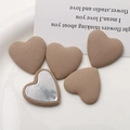 Macro detail of khaki fabric heart buttons showing striped texture and metal backing - Orange Brown