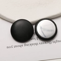Close-up of black leather covered round buttons with silver metal back for DIY crafts - Black