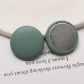 Detail view of round Morandi green litchi grain leather buttons with metal backing - Grey Green
