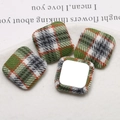 Macro detail of plaid fabric square buttons showing textile texture and metal flat back base - Green