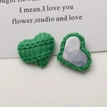 Detailed view of green knitted heart accessories with clear texture and metal base - Green