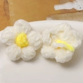 Dettaglio di due fiori all'uncinetto in peluche bianchi con centri gialli in un vassoio - Petalo Bianco Cuore Giallo