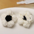 Detail of two handmade plush crochet puff flowers in black and white for DIY accessories - White With Black Heart