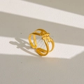Détail macro de la bague nœud dorée avec ombre élégante sur fond texturé blanc - Style Noeud Croisé Minimaliste (13) / Or
