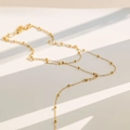 Primer plano de un collar en Y dorado con pequeñas cuentas y sombras elegantes de fondo - Collar en Y de Doble Capa Dorado (B62)
