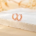 Close-up of minimalist rose gold huggie hoop earrings on a textured stone pedestal - Inner Diameter 6mm / Rose Gold