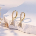 Gold letter A zircon drop earrings with pave hoop and polished finish on stone background - Gold A
