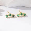 Elegant gold earrings with three green cubic zirconia stones on white stone pedestal - Gold Green Zirconia Earrings