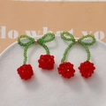Detailed view of handmade beaded cherry pendants with red crystal beads and green leaves - Red