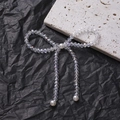 Detail view of crystal beaded bow with white pearls on a minimalist textured background - Handmade Beaded Bowknot (1 Piece)
