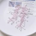 Detail of pink and white beaded tassel earrings with a botanical coral design on a tray - Pink