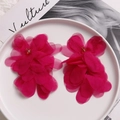 Close-up of handmade magenta mesh flower earrings with gold bead detail on a plate - Rose Red