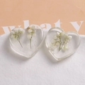 Macro detail of heart-shaped resin charms with white dried flowers and pearls inside - White Dried Flowers