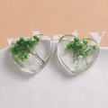 Macro shot of heart-shaped resin charms featuring real green dried flowers and white pearls - Green Dried Flowers