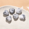 Macro detail of heart-shaped acrylic beads with black ink marble pattern for DIY jewelry - 1 Piece / Grayish White