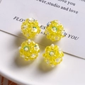 Detail view of four yellow beaded DIY spheres with white flower accents for jewelry making - Yellow