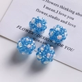 Detailed view of four blue faceted glass bead spheres with tiny white flower accents - Light Blue