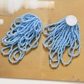 Macro view of blue crystal flower tassel earrings with intricate handmade beadwork - Blue