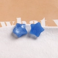 Detail of blue resin star charms with glitter finish on white textured base - Blue