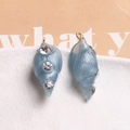 Gros plan de pendentifs conque en résine bleu clair avec strass et boucles en métal doré - Rose bonbon