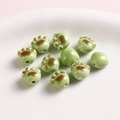 Macro shot of green ceramic cat paw beads for DIY jewelry with glossy finish - Green