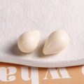 Macro shot of two cream-colored resin teardrop pendants for DIY jewelry making - White