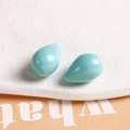 Macro shot of two light blue teardrop resin pendants with a polished mirror finish for DIY - Green
