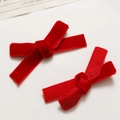 Close-up of a pair of bright red velvet ribbon bow hair clips on a white background - Red