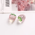 Close-up of semi-transparent pink resin strawberry charms with green leaves and hanging loop - Pink