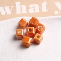 Close-up of glossy orange 9mm cubic ceramic beads with center hole for DIY jewelry - 1 Piece / Orange