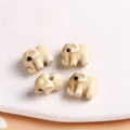 Close-up of four cream ceramic elephant beads with pre-drilled holes for DIY jewelry - 1 Piece / Light Coffee