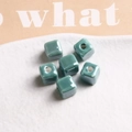 Macro shot of 9mm turquoise glazed ceramic cube beads with central holes for DIY jewelry - 1 Piece / Green