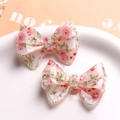 Floral resin bow hair clips in light pink featuring small red flower patterns - Red