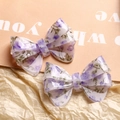 Set of two purple floral bow hair clips featuring translucent acrylic finish for styling - Purple