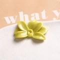 Close-up of a light green glossy resin flower charm for DIY jewelry on a white plate - Fruit Green
