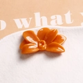 Macro shot of glossy orange flower resin accessory on minimalist textured background - Orange