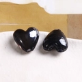 Dettaglio ravvicinato di due perle di vetro nere a forma di cuore per creazione gioielli - Nero e Grigio