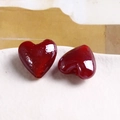 Macro view of two heart-shaped red glass beads with polished finish for DIY jewelry - Red