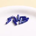 Macro-opname van blauwe marmeren cilindrische kralen op een wit keramisch dienblad voor DIY - Donkerblauw Witte Textuurkolom (24)