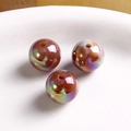 Macro shot of three baroque iridescent round acrylic beads with AB aurora coating for DIY - Iridescent Gold