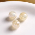 Macro view of three baroque iridescent round acrylic beads on a white ceramic surface - Glossy White