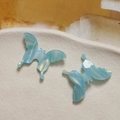 Detailed view of blue gradient acetate butterfly charms with 3D marble texture on ceramic - Blue